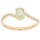 Oval green Peridot ring in 14K yellow gold with diamond accents, showcasing elegance and luxury.
