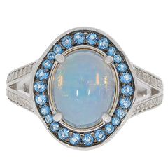 Oval white opal sterling silver ring accented with sparkling blue gemstones for elegant jewelry collection.