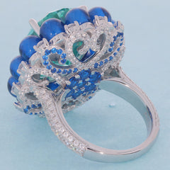 Elegant ring featuring a cushion green Moissanite center stone with blue gemstone accents in sterling silver setting.
