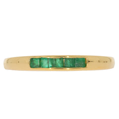 Elegant gold ring featuring five princess-cut green emeralds, perfect for adding sophistication to any jewelry collection.