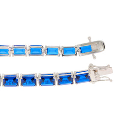Custom sterling silver semi mount tennis bracelet setting with emerald cut blue gemstones.