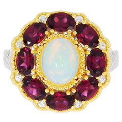 Elegant gold ring featuring red gemstones and a central white opal, showcasing luxurious design and craftsmanship.