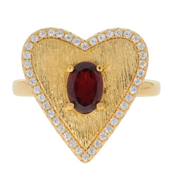 Heart-shaped gold ring featuring an oval red gemstone at center and surrounded by sparkling diamonds.