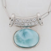 Oval blue Larimar Pectolite sterling silver pendant with sparkling gemstone accent, showcasing elegance and luxury.