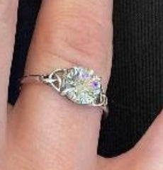 Sterling silver ring featuring a sparkling moissanite stone on a hand, showcasing elegant jewelry design.