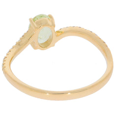 Oval green peridot set in 14K yellow gold ring, featuring a delicate band and diamond accent, showcasing elegant craftsmanship.