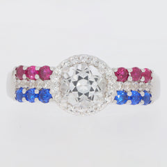 Elegant round white Moissanite ring with ruby and sapphire accents in sterling silver setting.