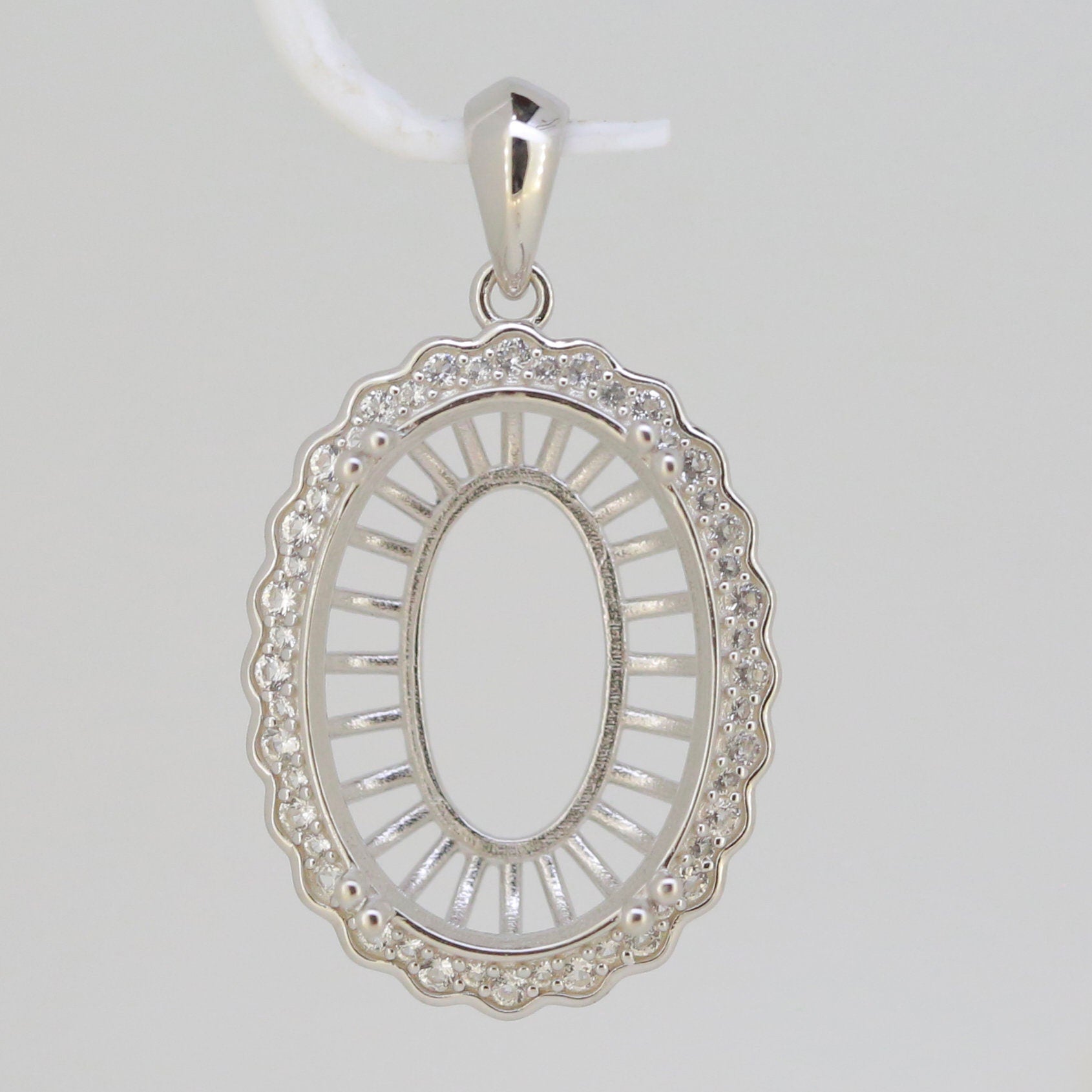 Sterling silver semi mount pendant setting oval shape with halo and white topaz accents, ready for custom gemstone.