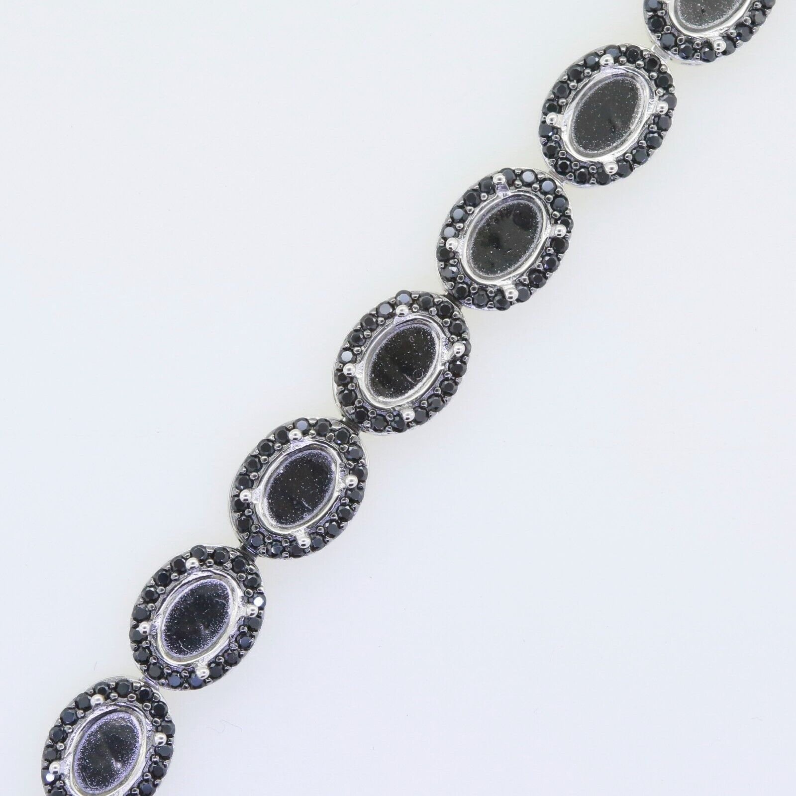 Sterling silver semi mount tennis bracelet setting with black spinel, featuring oval cabochons in a halo design.
