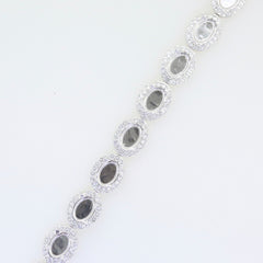 Sterling silver semi mount tennis bracelet setting featuring oval cabochon halo design with white topaz accents.