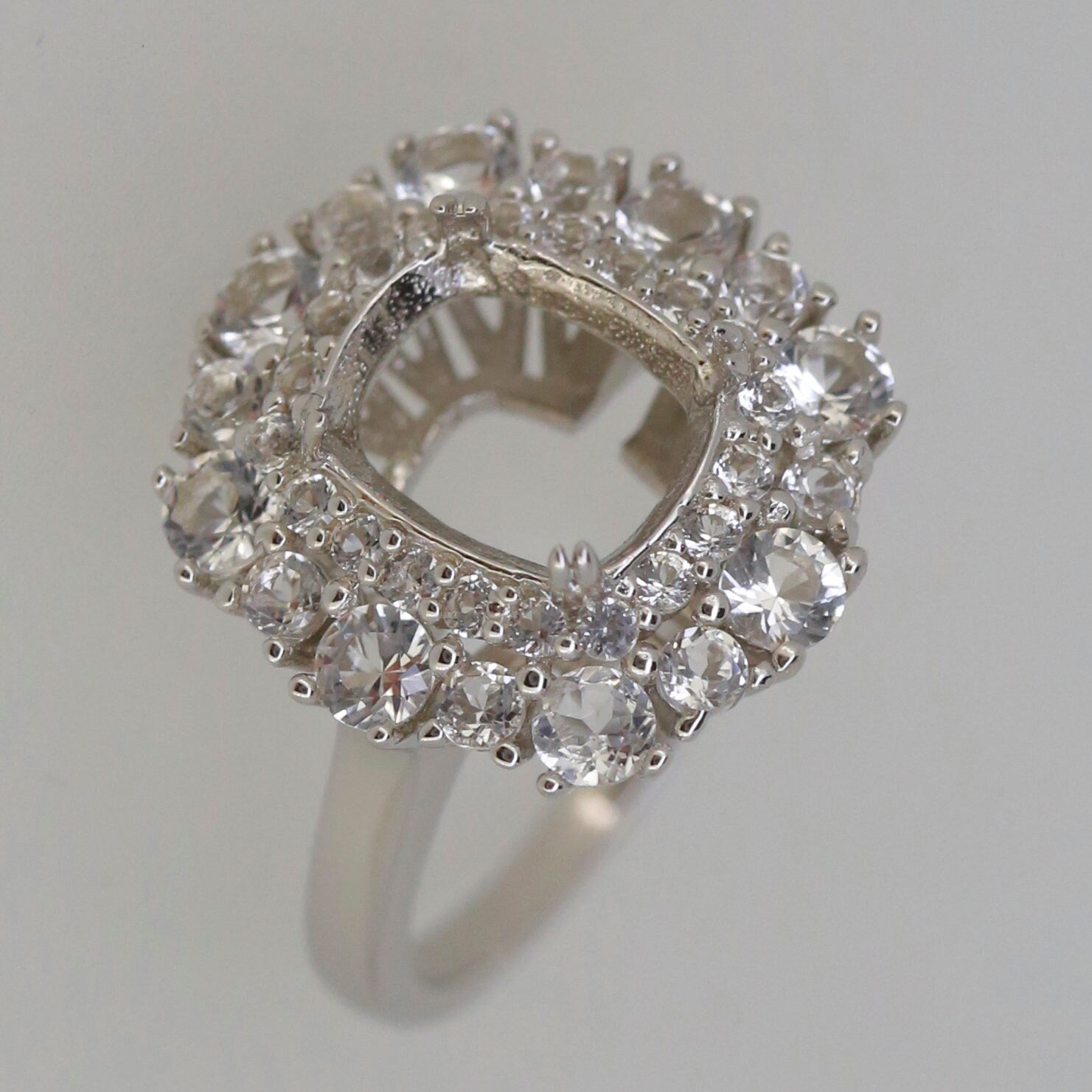 Sterling silver semi mount ring setting with halo of white topaz accents, designed for a 10x8mm cushion gem.