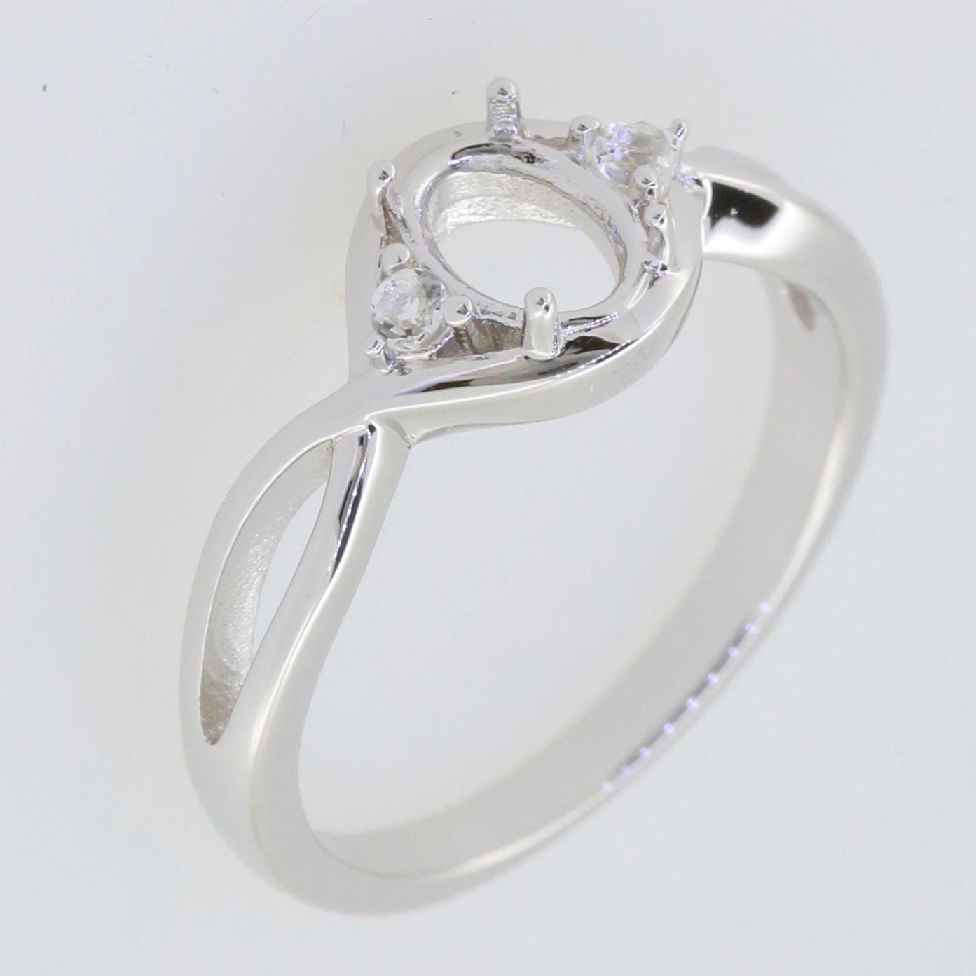 Sterling silver semi mount ring setting for 7x5mm oval gemstone with split shank design and white topaz accents.