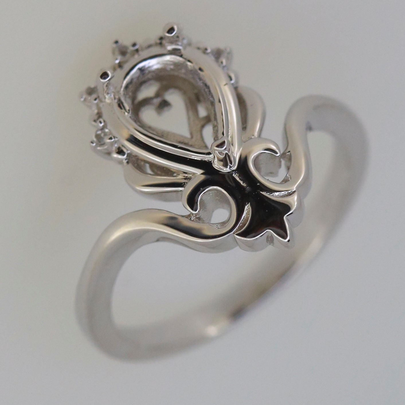 Sterling silver semi mount tiara ring setting with space for 9x6mm pear gemstone and white topaz accents.