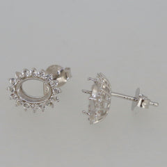 Sterling silver semi mount earrings setting with halo design for 8x6mm gemstone, featuring white topaz accents.