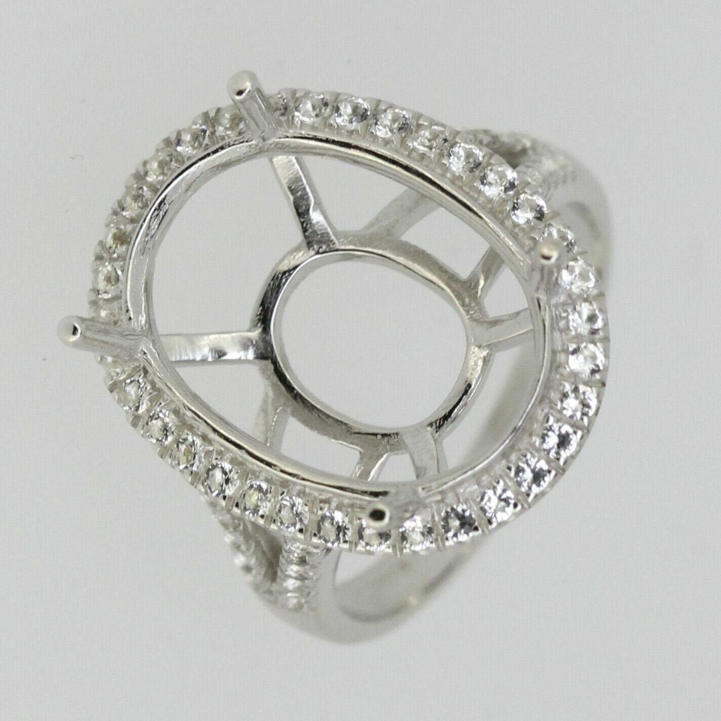 Sterling silver semi mount ring setting featuring an oval shape and white topaz halo, designed for custom gemstone placement.