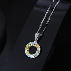Sterling silver round circle crystal pendant necklace on a black surface with an 18 inch adjustable chain.