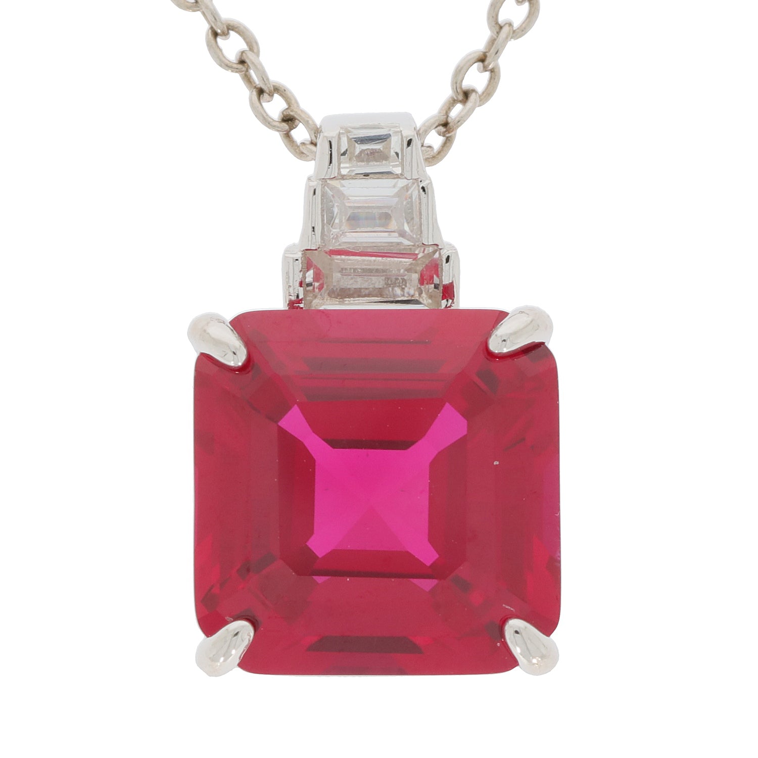Emerald cut red ruby pendant with Moissanite accents in sterling silver setting, elegant jewelry piece.