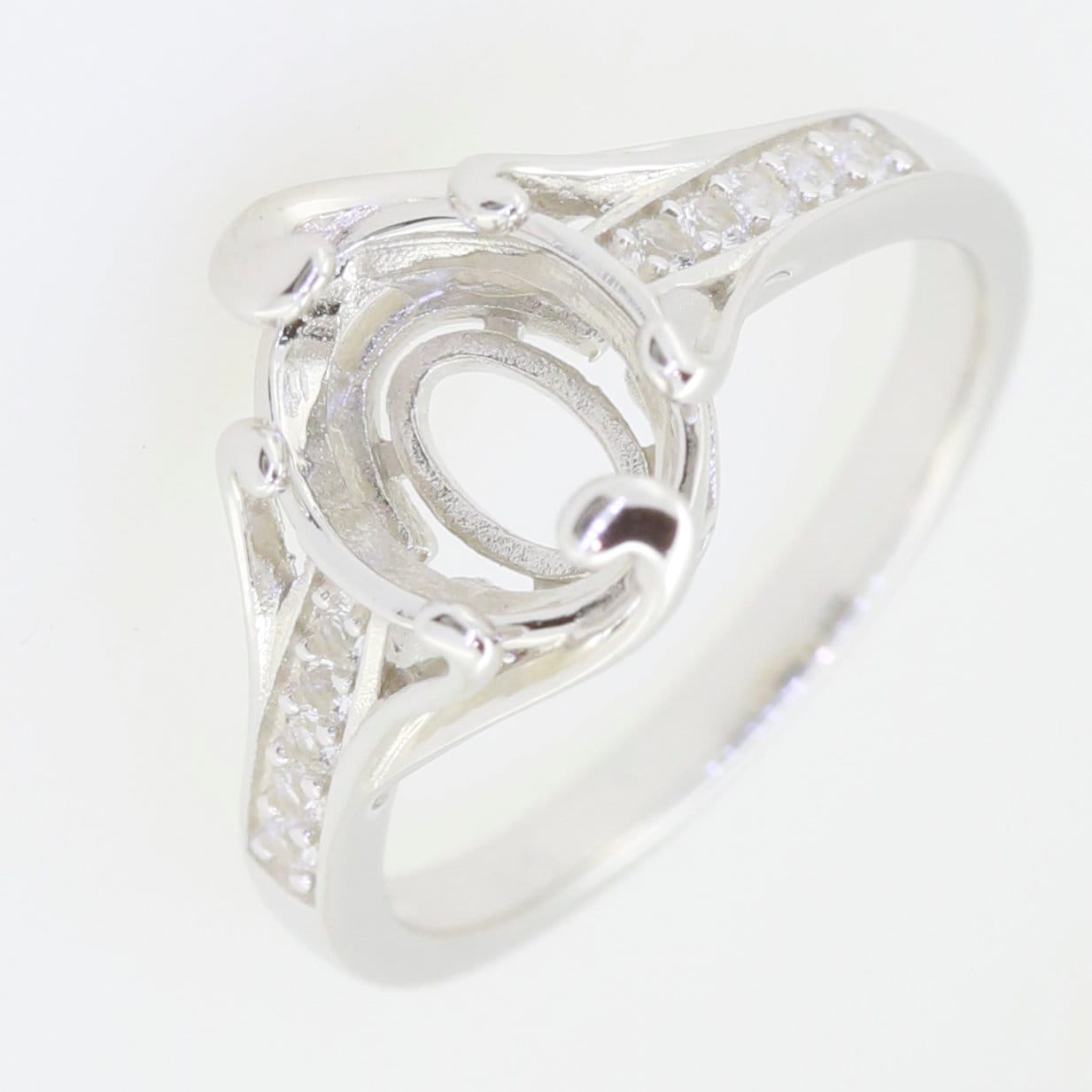 Sterling silver ring setting designed for an oval gemstone, showcasing intricate details and sparkling accents.