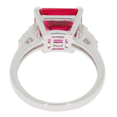 Elegant emerald cut red ruby sterling silver ring with moissanite accents, showcasing a luxurious design.