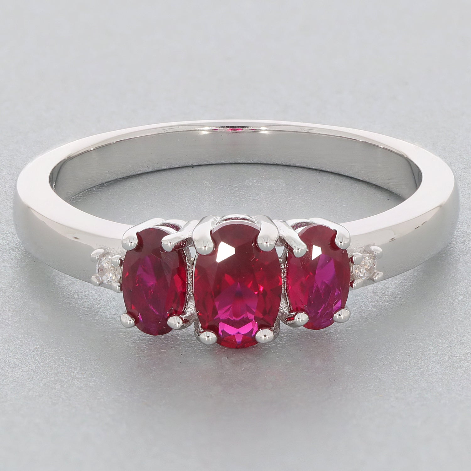 Red Ruby Sterling Silver Ring featuring three oval gemstones with accent stones, perfect for an elegant touch.