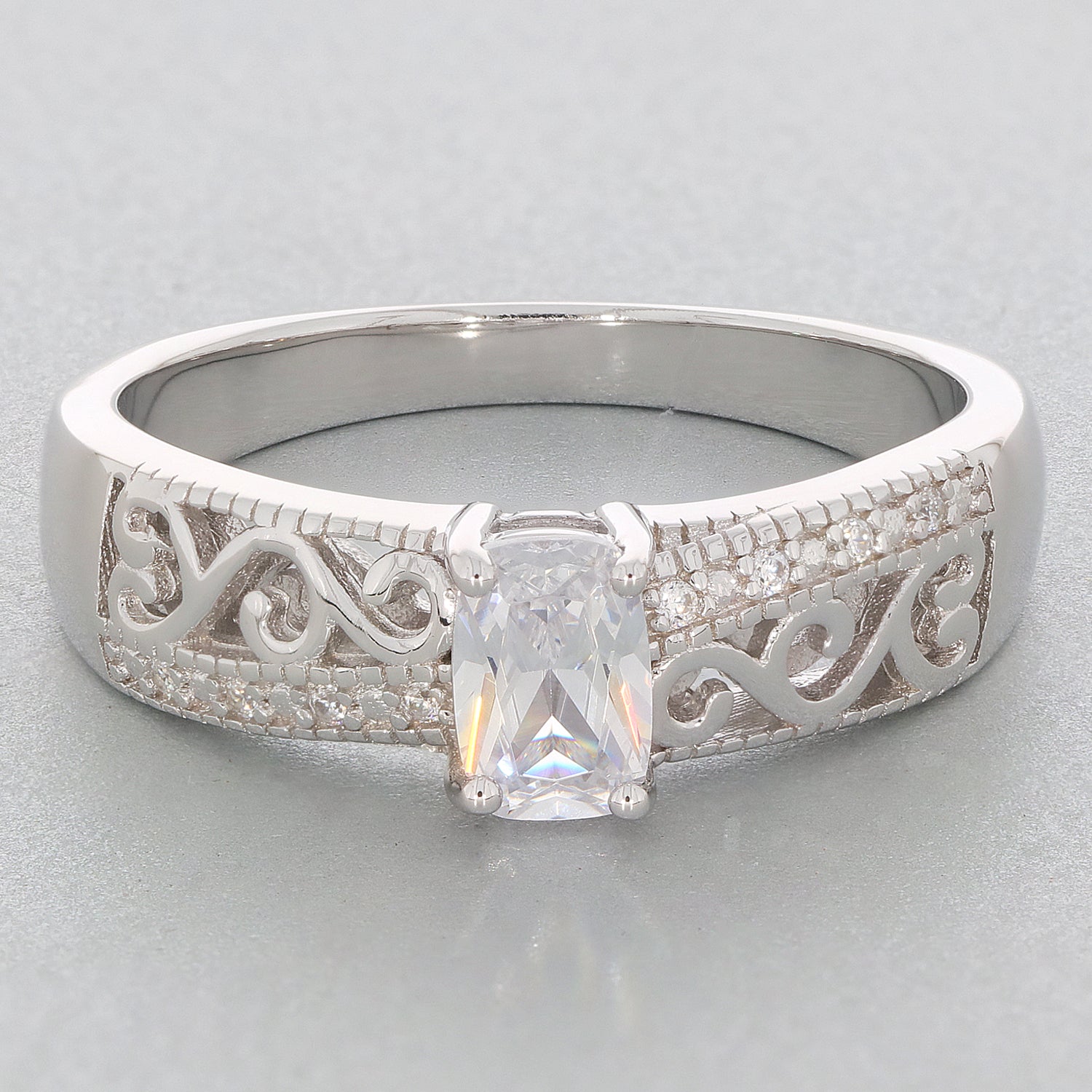 Cushion cut moissanite sterling silver ring with elegant filigree design and accent stones.