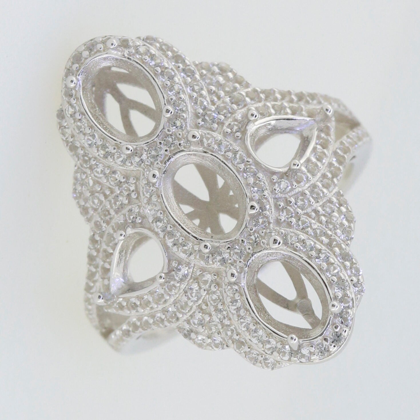 Sterling silver semi mount ring setting with intricate design and multiple stone settings, featuring oval and pear shapes.