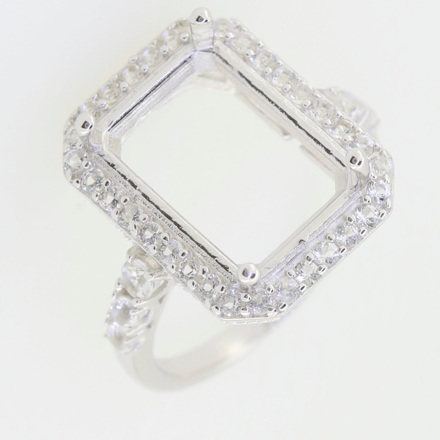 Custom sterling silver semi mount ring setting with white topaz accent for 12x10mm emerald, halo design.