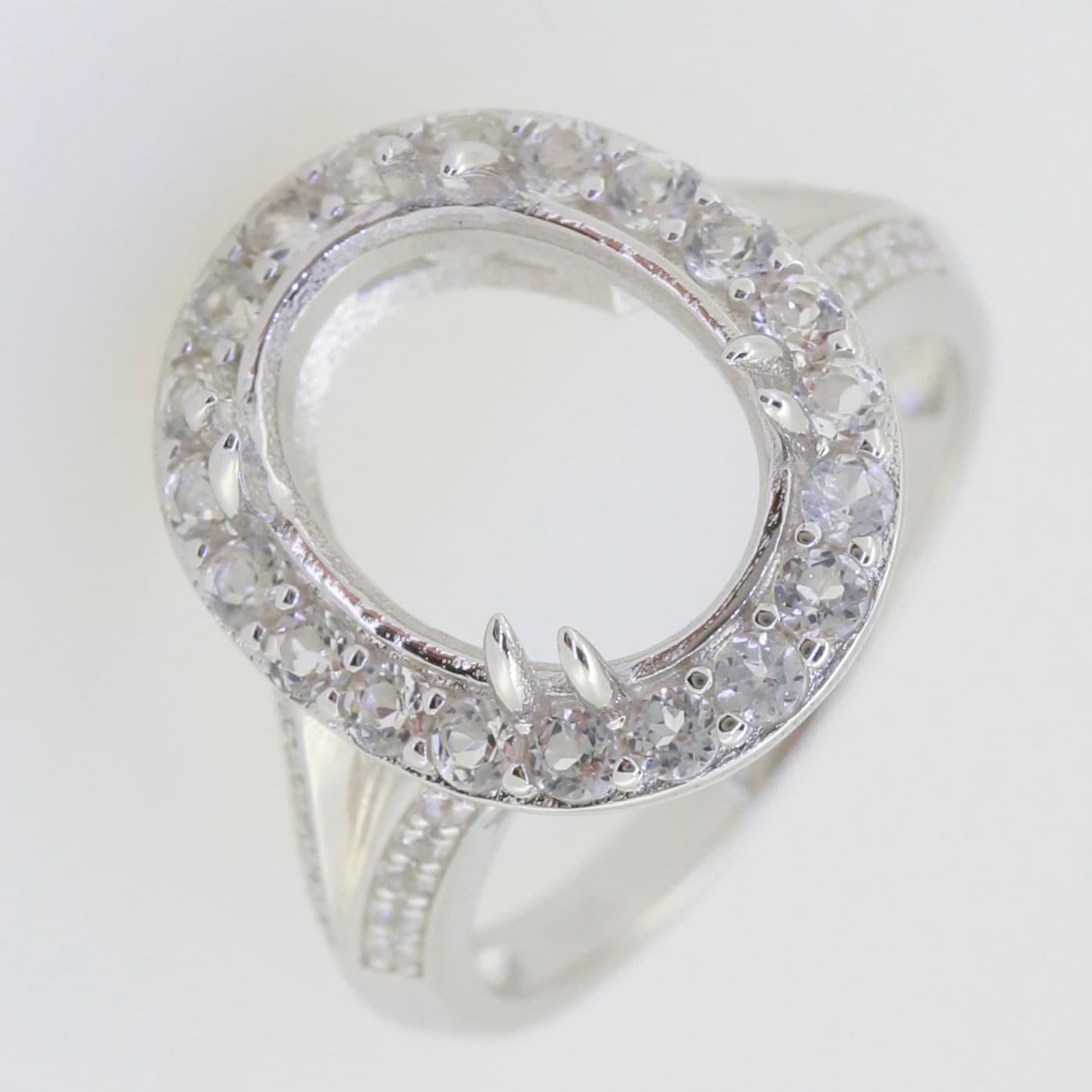 Sterling silver semi mount ring setting with halo of moissanite accents, designed for oval stones, split shank style.