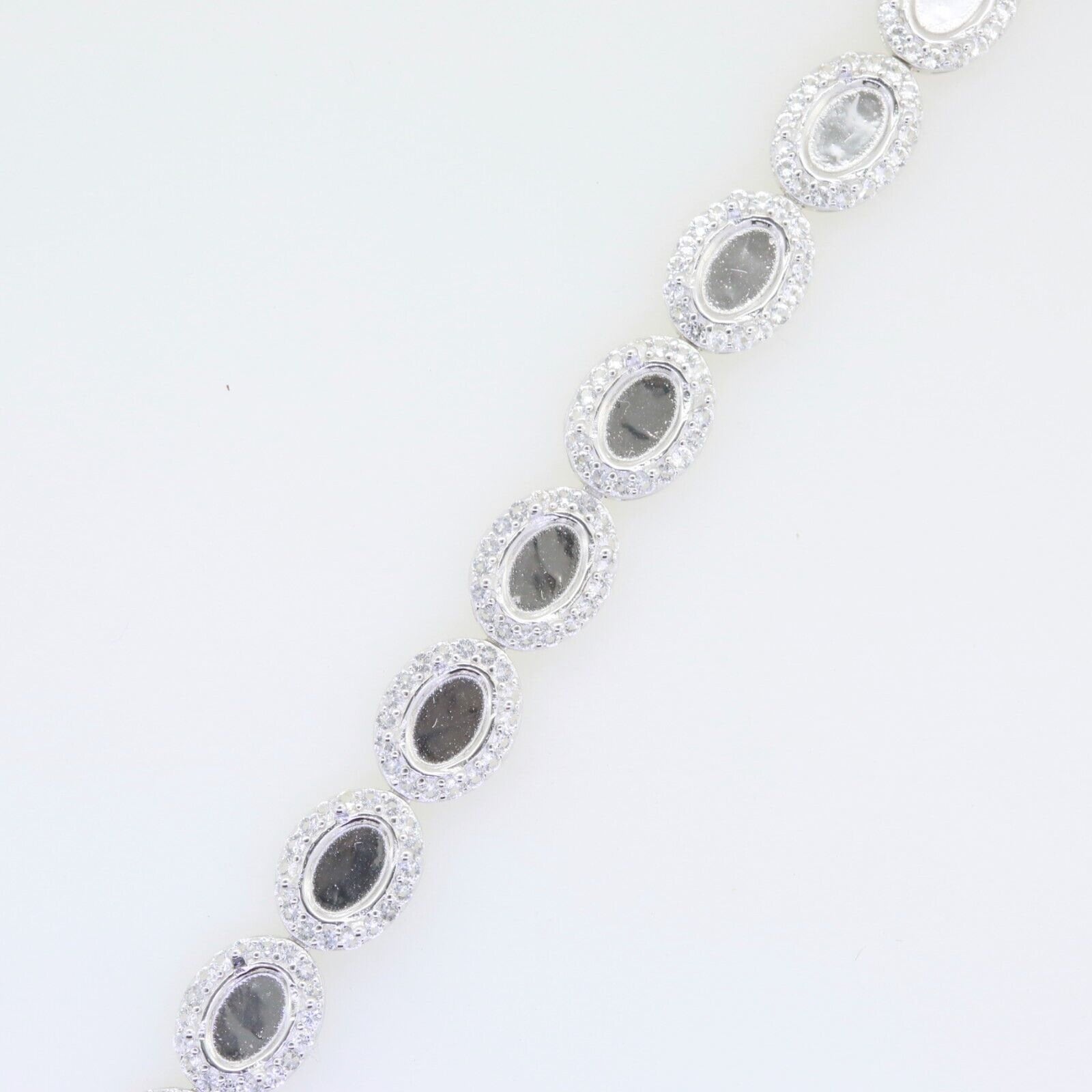 Sterling Silver semi mount tennis bracelet setting with oval cabochon halo and white topaz accents.