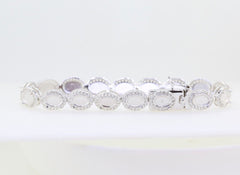 Sterling silver semi mount tennis bracelet setting with oval cabochon halo and white topaz accents.