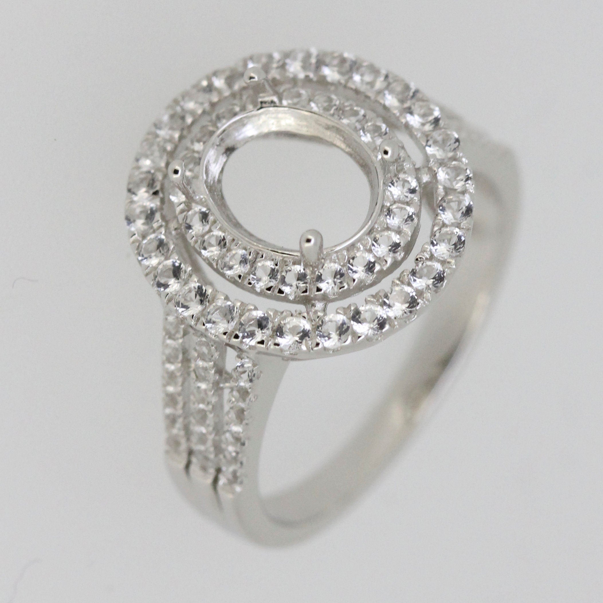 Sterling silver semi mount ring setting with white topaz halo and oval center for custom gemstone placement.