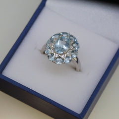 Sterling silver semi mount ring setting with natural aquamarine halo, suitable for 9x7mm oval gemstone, displayed in a jewelry box.