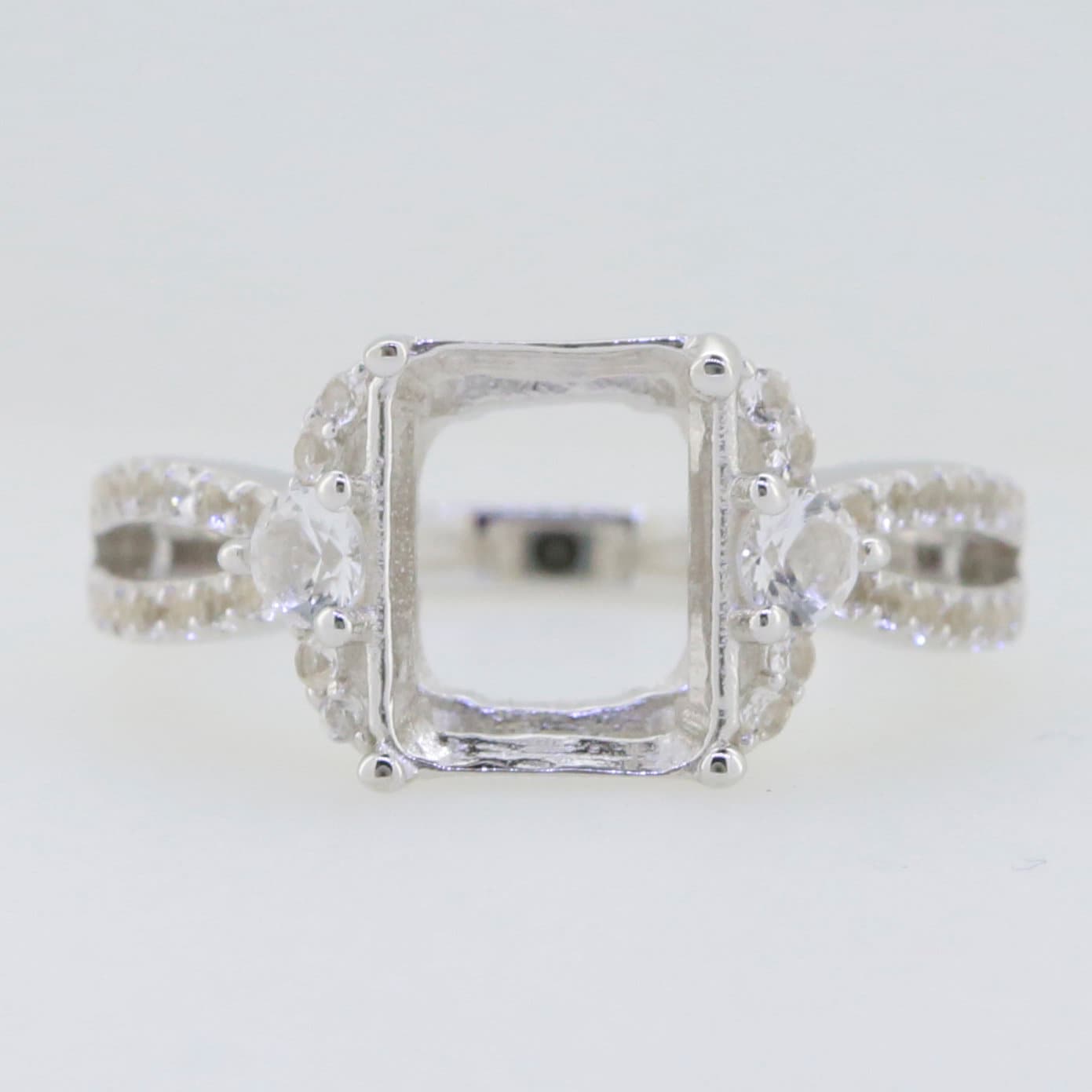 Sterling silver semi mount ring setting with moissanite accents and halo design, ideal for emerald gem placement.