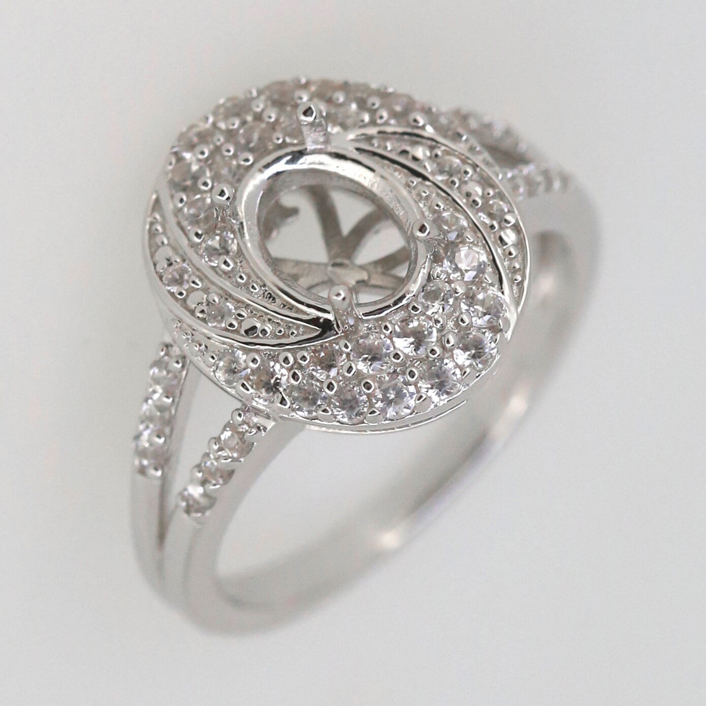 Sterling silver semi mount ring setting with oval design, split shank halo, and white topaz accents.
