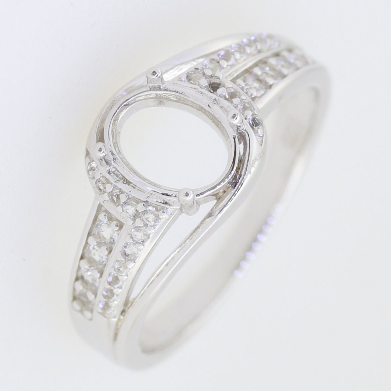 Sterling silver semi mount bypass ring setting with moissanite accents for 8x6mm oval gemstone.