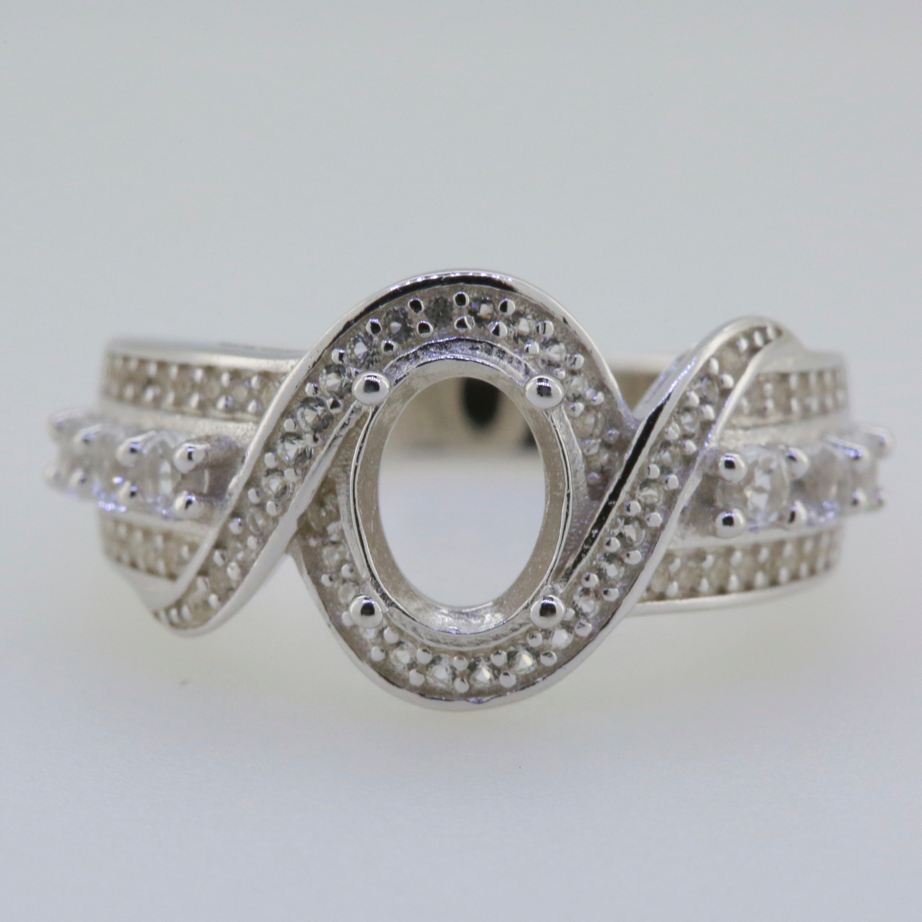 Sterling Silver Twisted Shank Semi Mount Ring Setting with Oval Halo for 8x6mm Gemstone and White Topaz accents.