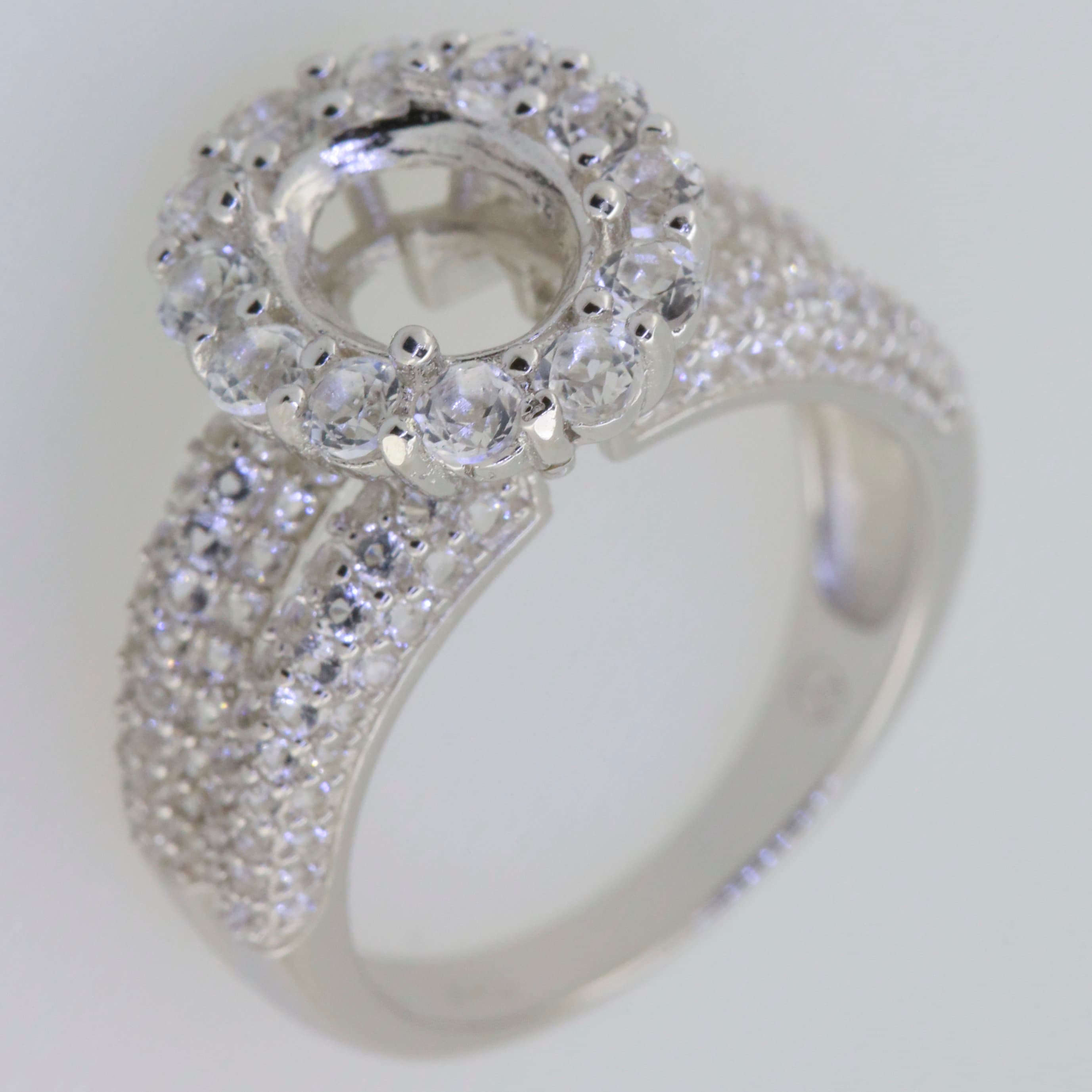 Sterling silver semi mount ring setting with halo, designed for oval 9x7mm gems, featuring White Topaz accents.